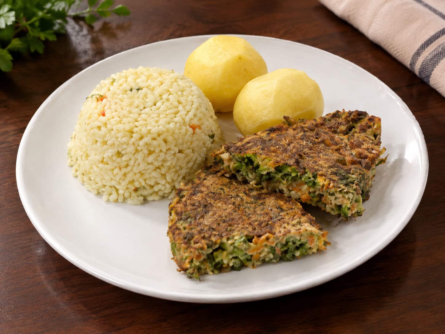 Dos trozos de tortilla de verduras servidos con arroz y papas cocidas
