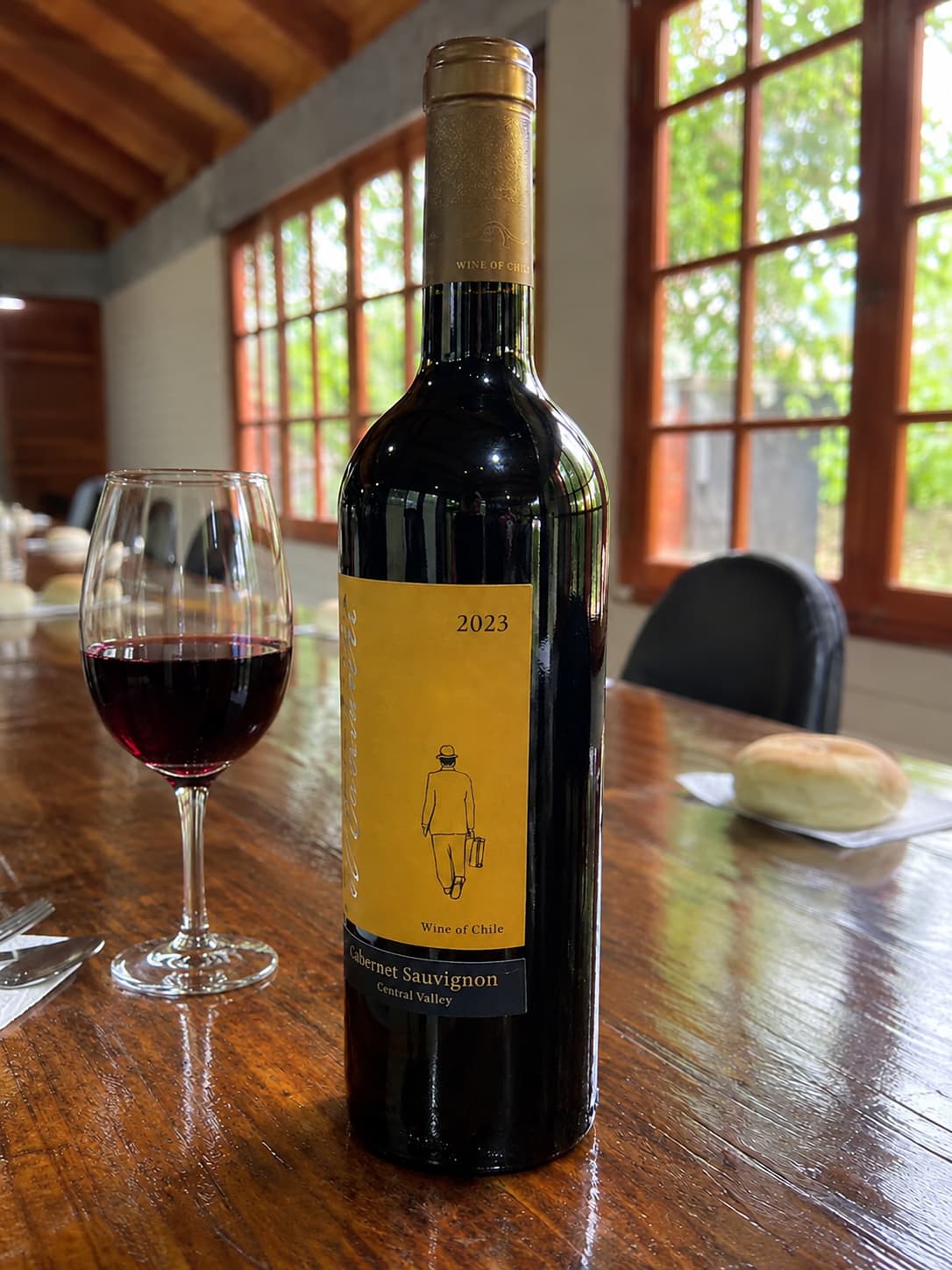 Botella de vino Cabernet Sauvignon chileno junto a una copa de vino tinto, sobre una mesa del salón de Pueblo Hundio